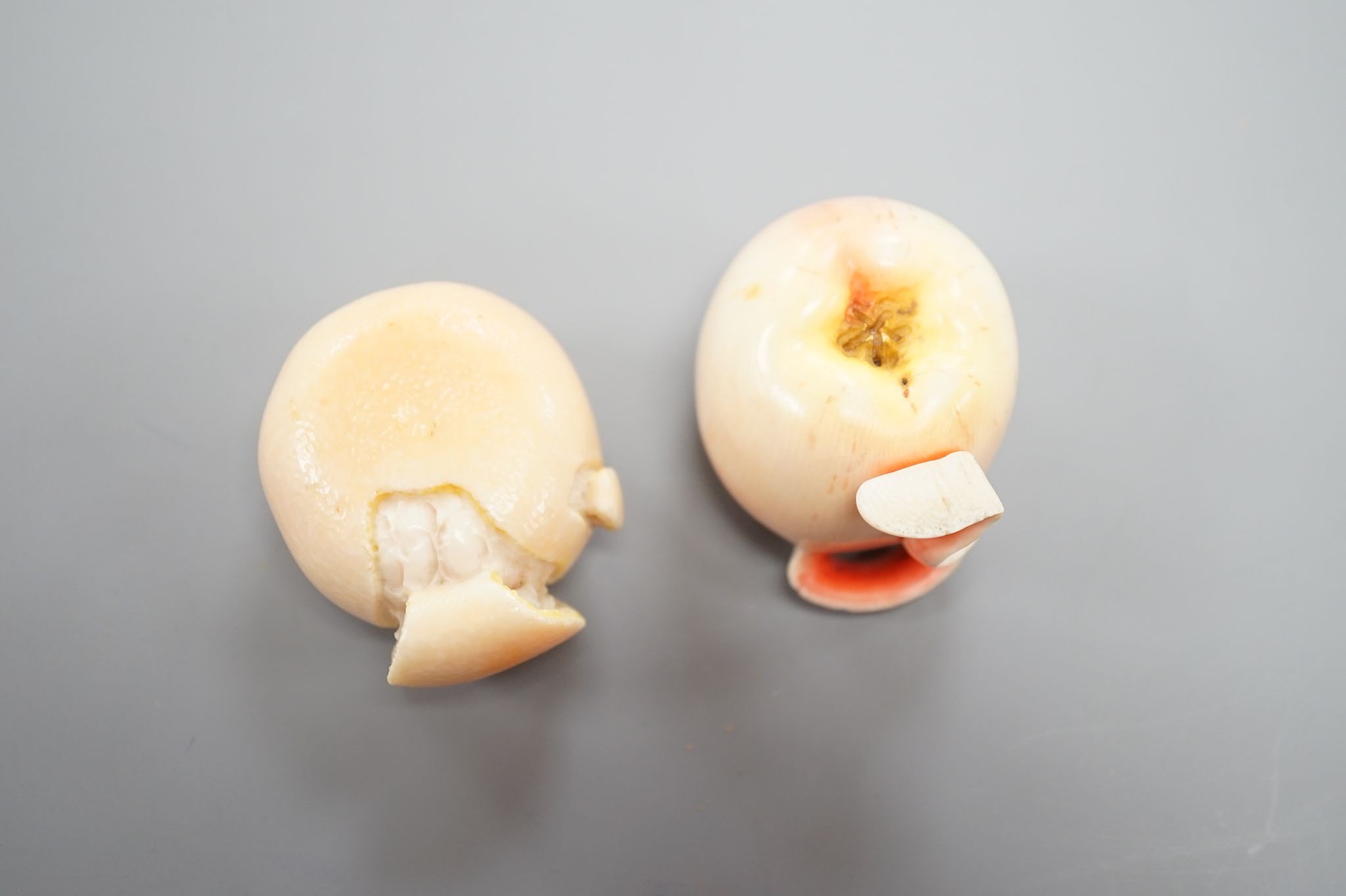 Two Japanese ivory models of a peeled apple and a satsuma, Meiji period, 3.5 cms high.